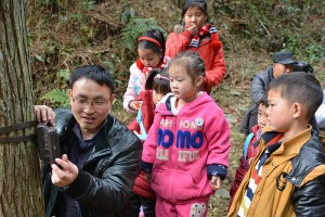 Fanjingshan nature reserve biologist Lei Si showed children how to mount a camera trap on a tree. (Photo by Kefeng Niu)